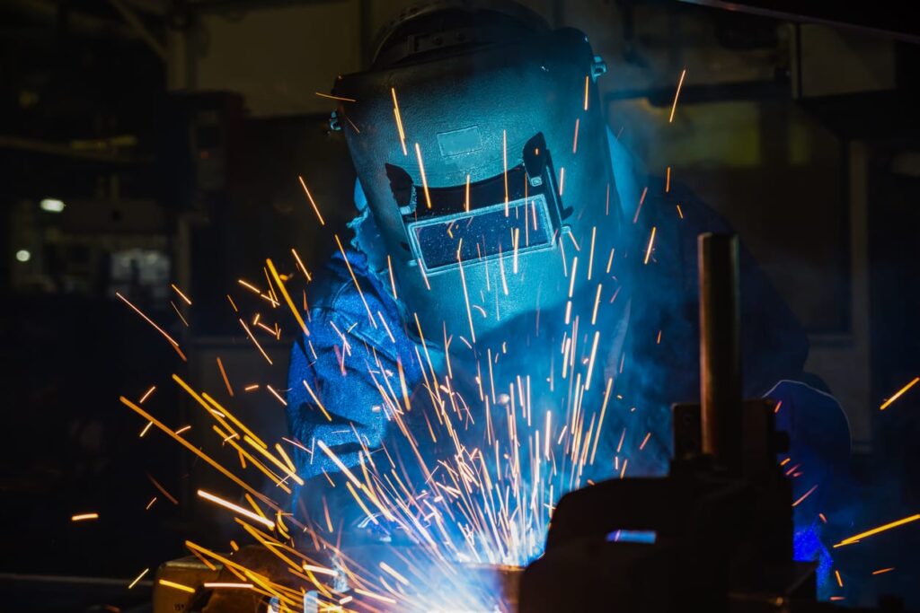 Industrial worker is welding metal in factory
